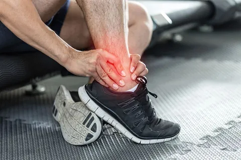 A man in a gym located in Millsboro and Seaford, DE, is holding his leg due to pain.